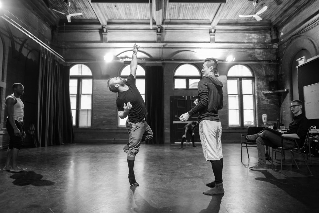 Indrit Kasapi and William Yong are choreographing in a beautiful bright studio. The photo captures a moment when Indrit strucks his arm upwards as William smiles