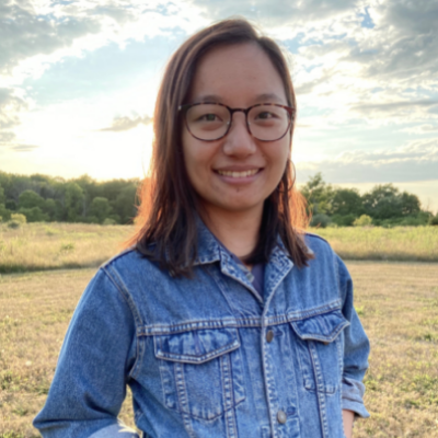 Graphic shows Tenzin, a Himalayan woman, standing in a field, smiling at the camera. She has light brown hair and wears glasses. She is wearing a jean jacket.