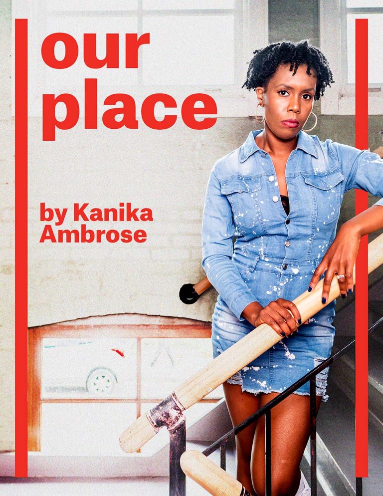 Our place by Kanika Ambrose. Kanika leans on a staircase, wearing short locks, hoop earrings, and a jean jacket dress. Her face rests calm as she stares into the camera from afar. Sunlight comes through the windows behind her brightly.