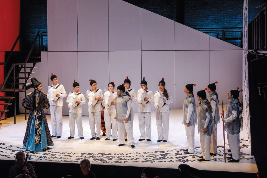 A arge group of people on a white stage wearing white talking to someone in elaborate blue robes.